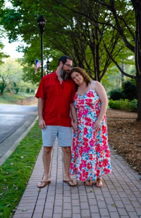 Engagement session photo of a couple on a tree-lined walkway