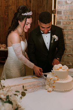 Bride and groom cutting the cake against an exposed brick wall