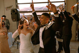 Guests dancing with raised hands around the couple at the reception