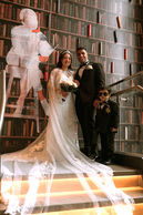 Bride's train and veil trailing down a staircase in a book-lined room