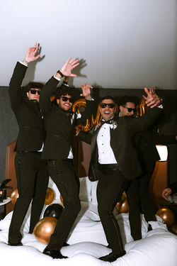 Groomsmen in sunglasses jumping and cheering together
